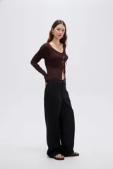 Top de manga larga en tejido de punto con lurex, color negro, de corte ajustado al cuerpo, con escote en V pronunciado y cierre delantero mediante finos lazos para anudar.
