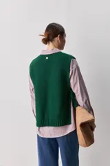 Chaleco tejido de punto color beige, con cuello redondo, terminaciones en rib y lazos laterales regulables que permiten ajustar la prenda.