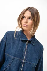 Campera de jean azul de silueta relajada, con cuello clásico, cierre frontal con cremallera metálica y bolsillos laterales.