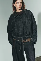 Cinturón de múltiples cadenas metálicas en tonos dorado envejecido y plateado. Presenta secciones de malla con diseño de rombos y dijes colgantes con grabados oscurecidos.