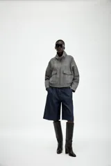 Chaqueta estilo bomber con estampado de cuadros, cuello subido, manga larga y cierre frontal con cremallera. Presenta bolsillos delanteros y bajo elástico.