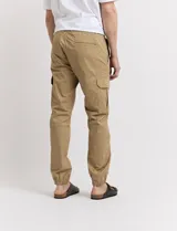 Pantalón de gabardina verde militar, corte cargo con bolsillos laterales con fuelle y tobillos ajustados con elástico.
