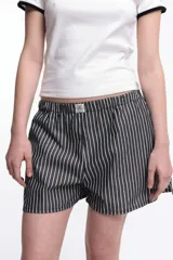 Short de popelina de algodón con diseño de rayas verticales grises y blancas, de tiro bajo, con cintura elástica y etiqueta con logo en el centro.
