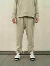 Pantalón de jogging estilo relaxed fit, confeccionado en felpa color beige, con cintura elástica, puños en los tobillos y logo de la marca sutilmente estampado en la pierna.