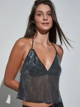 Top de lentejuelas plateadas, con escote halter y diseño fluido semitransparente.