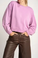 Buzo lila oversize confeccionado en 100% algodón, con cuello redondo, mangas largas y puños y dobladillo acanalados. Presenta un pequeño detalle bordado en el bajo.