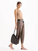 Bolso tipo hobo confeccionado en cuero vacuno negro con efecto rugoso y acabado suave. Presenta manijas finas para llevar al hombro, costura central vertical y un pequeño llavero de cuero colgante con el logo de la marca.