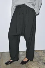 Pantalón de tiro bajo, color gris oscuro jaspeado, de corte muy holgado (baggy) y tiro caído. Posee cintura elástica ajustable con cordones y pinzas delanteras.