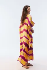 Kaftan maxi amplio de color amarillo, con escote redondo, mangas cortas y ruedo irregular. Presenta un diseño estampado a cuadros con efecto teñido.