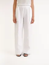 Pantalón blanco de lino con diseño de corte recto y amplio, bolsillos laterales superpuestos y cintura elástica.