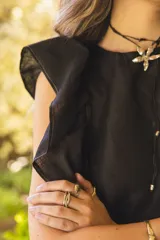 Blusa negra de lino con volados en los hombros y pespuntes en color beige.