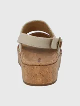Sandalias de cuero color marrón con plataforma de corcho, tira ancha de cuero sobre los dedos y tira trasera de tela color beige con hebilla.
