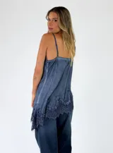 Top de viscosa color lila con efecto acid wash, tirantes finos y detalles de encaje floral en el escote y en el ruedo asimétrico.
