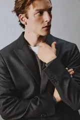 Blazer de corte regular confeccionada en lana de origen italiano, con diseño a cuadros sutiles. Presenta cuello con solapas de pico, cierre frontal de botones, bolsillos de solapa en la cadera y bolsillo de vivo en el pecho.