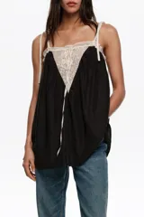 Top de diseño fluido en color negro con detalles de encaje blanco en el escote y tirantes finos regulables con lazos.
