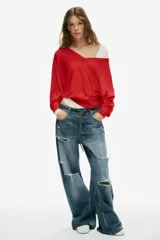Jeans de tiro medio y corte baggy con cinco bolsillos, trabillas y rotos decorativos. Cuenta con detalle de cinturón confeccionado en el mismo tejido y cierre frontal con cremallera y botón metálico.