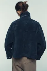 Cazadora estilo bomber confeccionada en piel, con cuello solapa, manga larga y cierre frontal con cremallera oculta y botones a presión. Presenta bolsillos delanteros de plastrón con solapa y botón a presión.