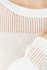 Blusa de tejido de punto color blanco, con cuello redondo, mangas largas y detalle de textura acanalada en la parte superior y en los puños.