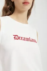Musculosa blanca corta con estampado de la palabra "Dreamland" en color rojo.