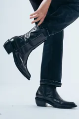 Bota de caña media confeccionada en cuero negro con acabado brillante, diseño de silueta limpia, puntera cuadrada y taco cuadrado de altura media.