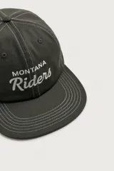 Gorra de algodón color negro con visera plana y bordado frontal en contraste con las palabras "MONTANA Riders".