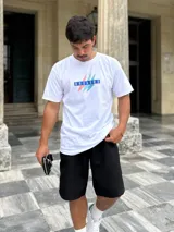 Remera blanca de algodón con estampa frontal que incluye la palabra "Brokers" en letras azules dentro de un rectángulo y dos rayos en celeste y salmón.