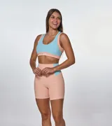 Conjunto deportivo de dos piezas compuesto por un top y un short de tiro alto. El top presenta un diseño de bloques de color en salmón y celeste con escote redondo y espalda deportiva. El short es de corte ajustado, con paneles laterales en contraste de color y textura acanalada.