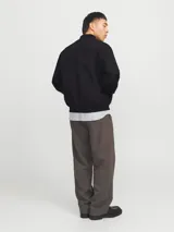 Campera bomber negra Jack & Jones de tejido plano liviano, con cuello baseball, cierre frontal de cremallera, bolsillos delanteros y puños de canalé. Confeccionada en poliéster y poliéster reciclado.