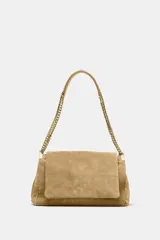 Bolso de hombro confeccionado en piel de ante color tostado, con diseño acolchado mediante pespuntes horizontales y verticales. Cuenta con una correa de cadena metálica dorada con refuerzo de piel y cierre mediante solapa con imán.