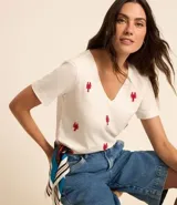 Remera de mangas cortas color crema, confeccionada en tejido flamé, con escote en pico y bordado delantero de langostas rojas.