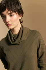 Polera de tejido de punto color naranja con cuello alto de caída relajada y diseño de líneas en relieve. Presenta una silueta holgada con hombros caídos y mangas largas.