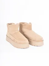 Bota corta tipo ugg con plataforma dentada, confeccionada en material gamuzado color beige con interior forrado en piel sintética.