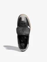 Zapatillas Adidas Samba LT, color negro con las tres tiras blancas y suela de goma marrón.