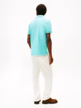 Chomba celeste de Tommy Hilfiger, corte regular, con cuello tipo polo, cartera de dos botones, mangas cortas y logo bordado en el pecho.