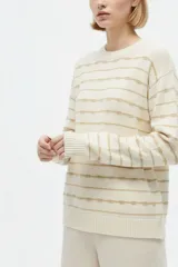Sweater de punto color blanco con diseño de rayas horizontales doradas, cuello redondo y manga larga.
