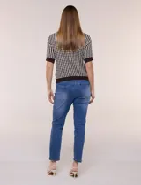 Cardigan de punto con patrón geométrico bicolor en gris y blanco, de manga corta, cuello polo y cierre frontal con botones nacarados.