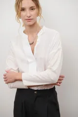 Blusa de color blanco hueso con cuello mao y escote en V, de corte holgado y mangas largas con caída relajada.