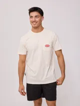 Remera de hombre color beige de corte regular fit, con manga corta, bolsillo frontal en el pecho y parche con logo bordado.