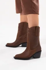 Bota de caña media de cuero marrón con acabado texturado, diseño de estilo western, tiradores laterales y taco medio cuadrado.