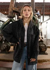 Campera tipo overshirt de paño jaspeado en color negro, con calce oversize, capucha y cordones trenzados. Presenta un diseño versátil con interior suave y abrigado.