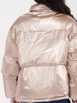 Campera puffer de corte oversize en tono champagne metalizado, con cuello alto envolvente y acabado brillante.