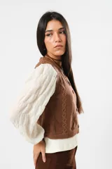 Blusa color manteca de cuello redondo y mangas largas abullonadas con puños elásticos.