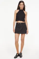 Top de punto estilo halter, color crudo, con cuello alto ajustado, diseño sin mangas y corte corto.