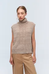 Chaleco de punto azul con cuello alto y diseño de trenzas.