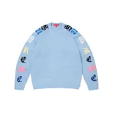 Sweater de punto en color celeste con cuello redondo. Presenta el logo de la marca Supreme estampado en tipografía Old English a lo largo de ambas mangas en colores variados.