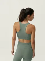 Top deportivo verde con cremallera frontal, de sujeción alta y tejido Shape_Tech con tecnología Performance.