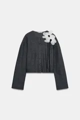Chaqueta gris de punto con cuello redondo, manga larga y cierre frontal con botones. Detalle de flor blanca y negra en el frente. Tejido en rib.