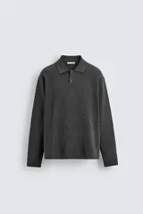 Polo de punto de manga larga con cuello solapa y cierre frontal de botones. Presenta un diseño de corte regular con aberturas laterales en el bajo.