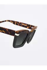 Lentes de sol Tiwi modelo Mali con montura gruesa bicolor: parte superior con estampado carey y parte inferior negra con detalle blanco en la esquina.