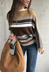 Sweater de punto con diseño de rayas horizontales en tonos chocolate, mostaza, blanco y gris. Presenta cuello redondo, mangas largas y corte holgado.
